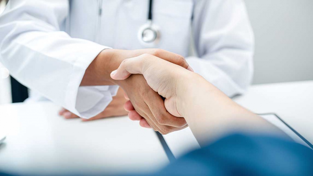 Пациент и врач на приеме уролога жмут руку